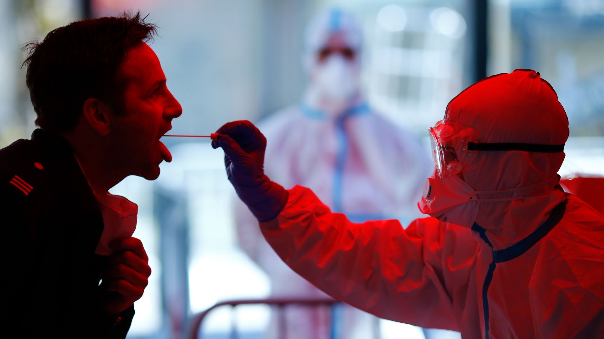 Mann wird von Person in Schutzanzug auf Corona getestet.