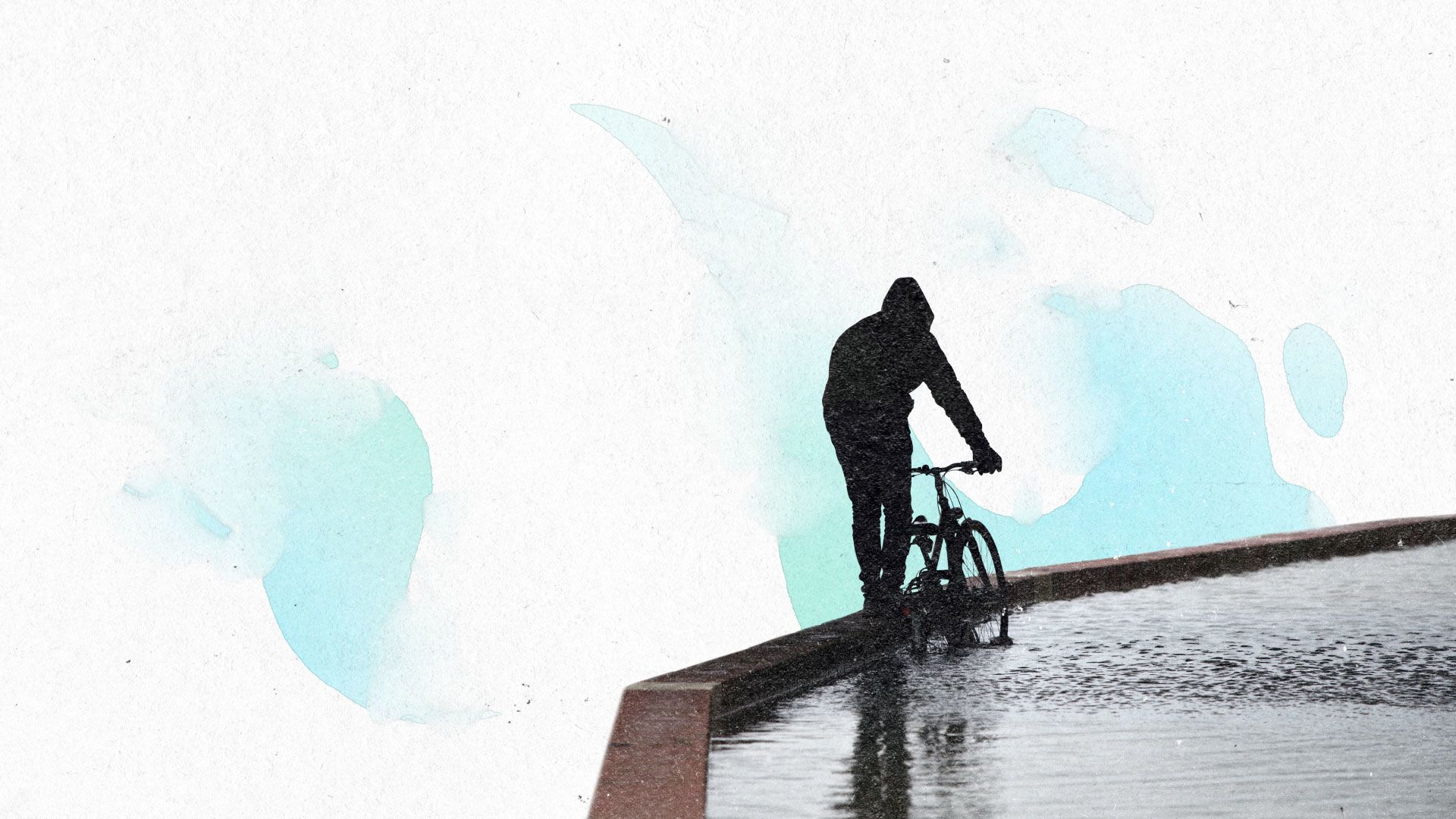 Ein Mensch steht auf einer Mauer und schiebt sein Fahrrad durch eine geflutete Fläche.